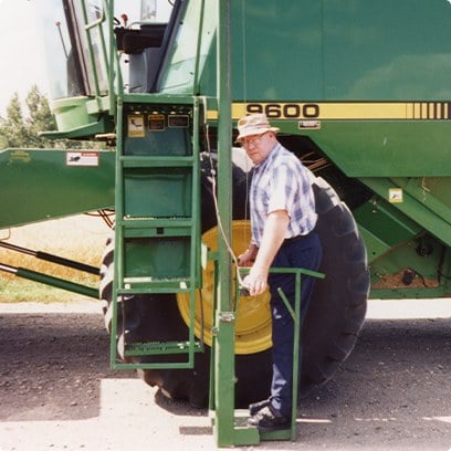 A farmer stepping down the ladder of a combine harvester