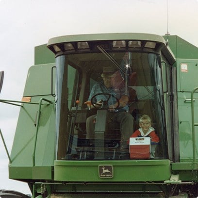 A farmer and a young child seated together in a combine cab